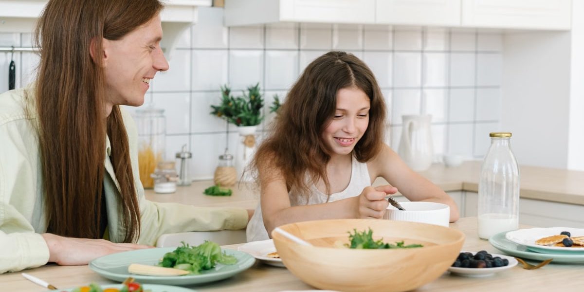 Father and daughter sharing a joyful breakfast at home in the kitchen.