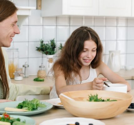 Father and daughter sharing a joyful breakfast at home in the kitchen.
